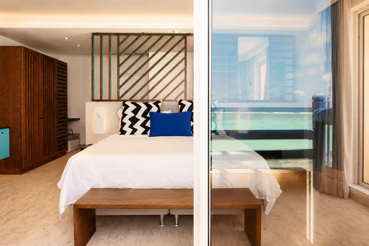 Best on Beach - King-size bed with bold patterned cushions and contemporary wooden detailing in a bright hotel bedroom.