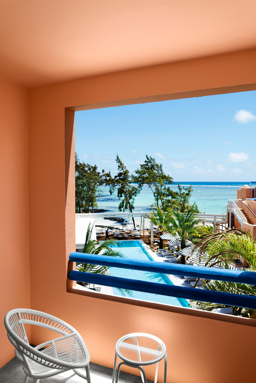 Seaview Room - Balcony overlooking the pool, palm trees and turquoise lagoon by the sea.