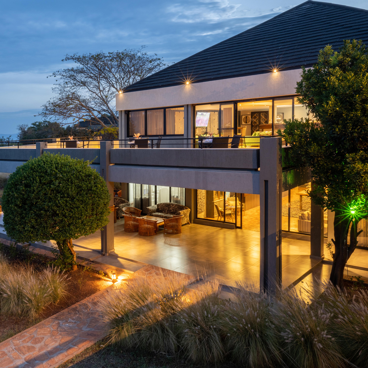 Exterior of SALT of Akagera surrounded by greenery at dusk.