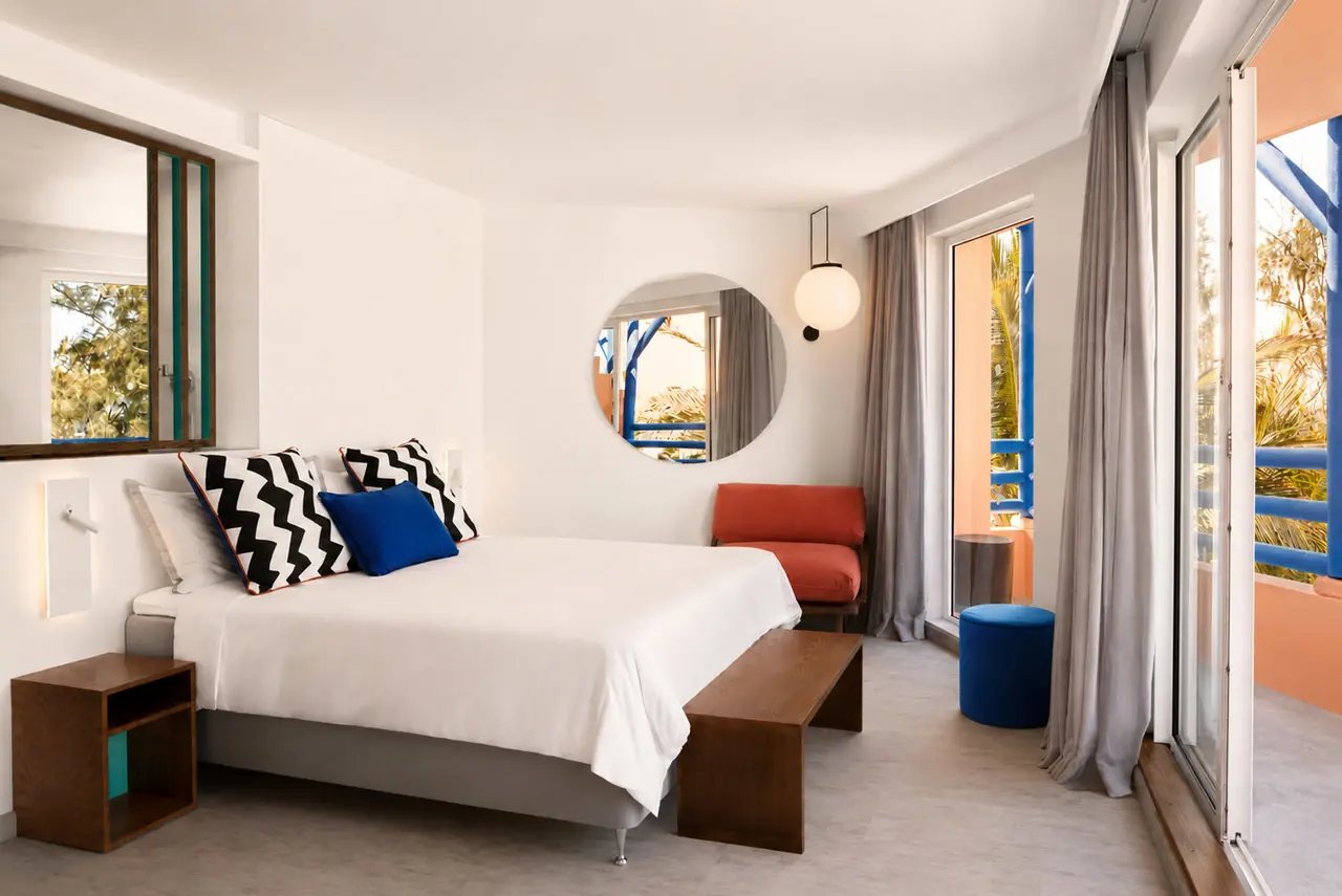 Pool Plus - Modern hotel bedroom with a private balcony, colourful design accents, and views of tropical greenery.
